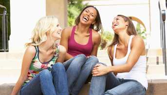 Three young women sitting on steps laughing