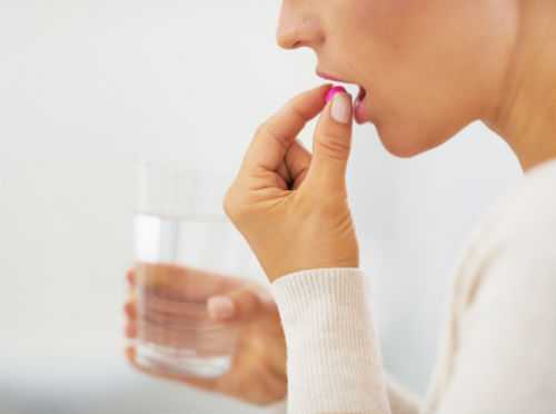 Woman taking pill with glass of water