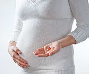 Pregnant woman holding medications.