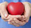 Person in blue scrubs holding a heart-shapped stress ball in hands.