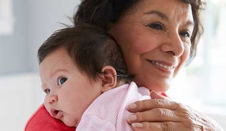 grandmother holding infant granddaughter against her shoulder