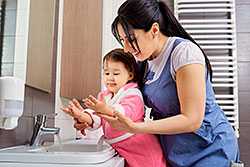 Mother helping toddler wash hands