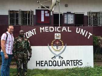 Greg (a la izquierda), detective de enfermedades de los CDC, posa fuera de la Unidad Médica Conjunta en Sierra Leona.