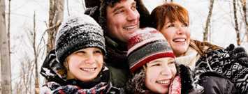 Familia con ropa de invierno disfrutando nevada en exteriores