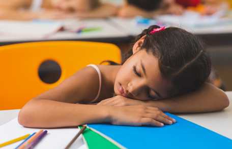 Una niña durmiendo en la clase.