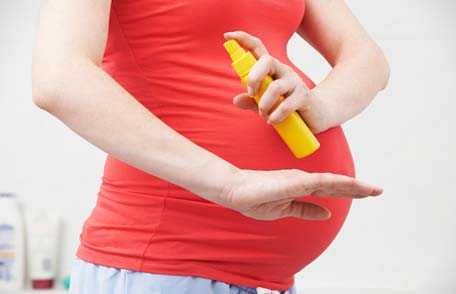 Mujer embarazada usando repelente de insectos.