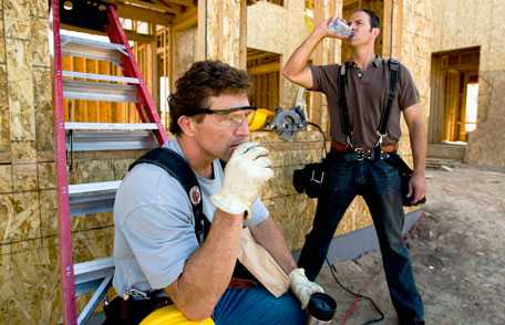 Trabajadores de construcción toman un descanso y beben agua.