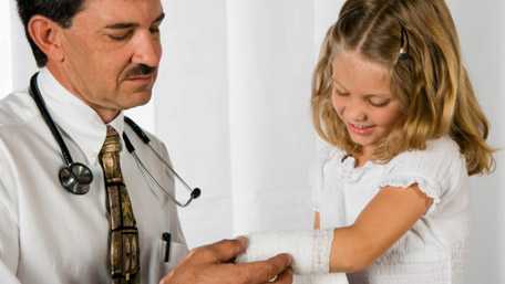 Foto de médico vendando el brazo de una niñita