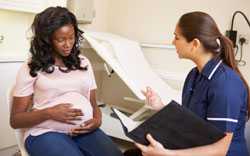 Mujer embarazada compartiendo información sobre su trabajo con su médica