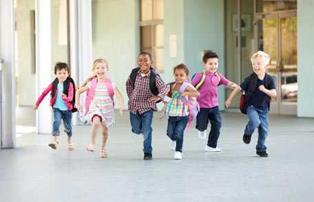 Niños corriendo en frente de la escuela