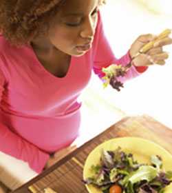 Una mujer embarazada comiendo una ensalada