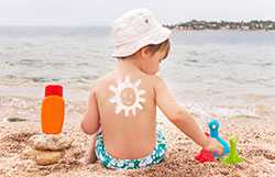 Protector solar en forma de sol sonriente en la espalda de un niño.