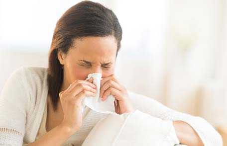 Una mujer estornuda en un pañuelo desechable. 