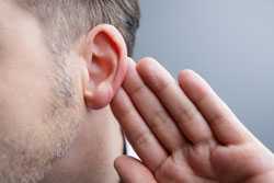 Hombre pone la mano detrás de su oreja para escuchar mejor.