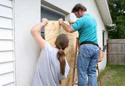 Dos personas asegurando una ventana con una placa de madera