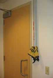 Tubo para guardar las señales de piso mojado plegables montado en una pared cerca de una puerta