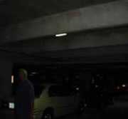 Área de estacionamiento muy oscura con un vehículo y una persona que apenas se ven
