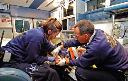 Perfil de dos paramédicos en una ambulanza que atienden a un paciente en una camilla
