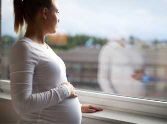 Foto: Una mujer embarazada mirando por una ventana
