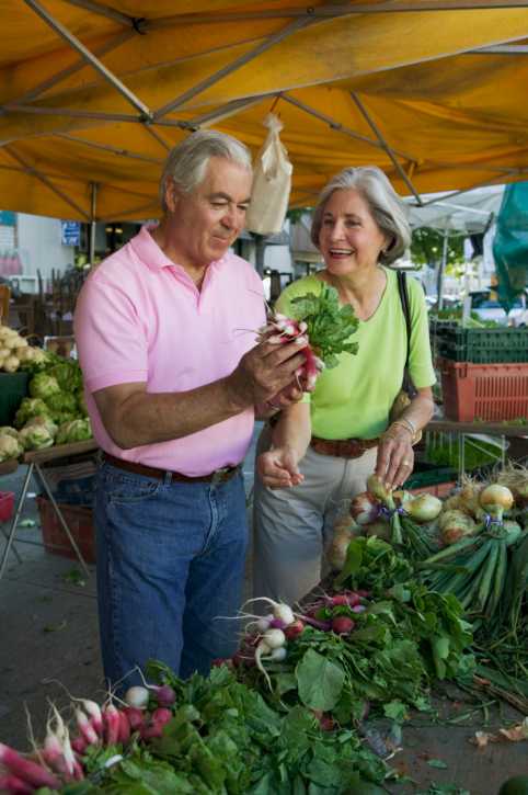 A couple looking at vegetables at a farmer's market.