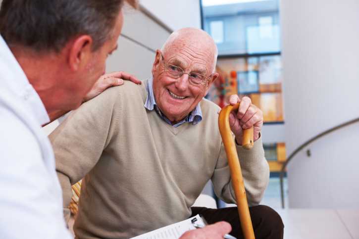 Man with a cane smiling at his doctor.