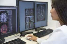 Photo: female doctor looking at digital brain scan images