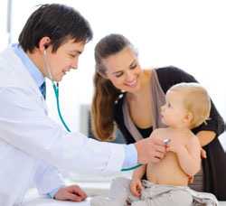 Una mamá sonríe mientras el doctor escucha el latido del corazón de su bebé por medio de un estetoscopio.