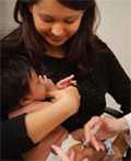 mother holding infant while getting vaccinated