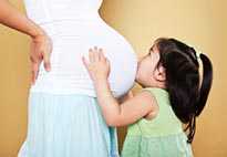 girl kissing pregnant woman's belly
