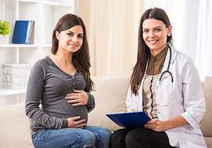 Pregnant woman sitting with doctor