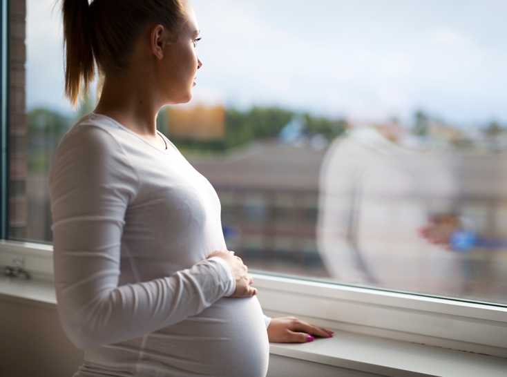 Pregnant woman looking at window