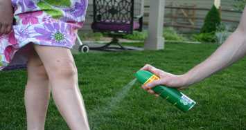 bug repellant being sprayed onto a girls legs