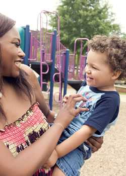 african american woman and child laughing and playing on a playground