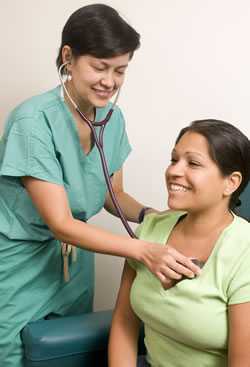 health professional listening to a woman's chest with a stethescope