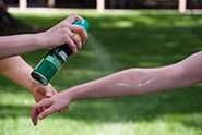 Person applying insect repellant to a child's arm