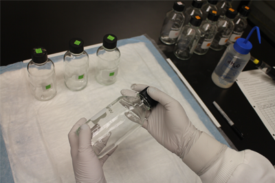 Persona en un laboratorio sosteniendo una botella de vidrio.